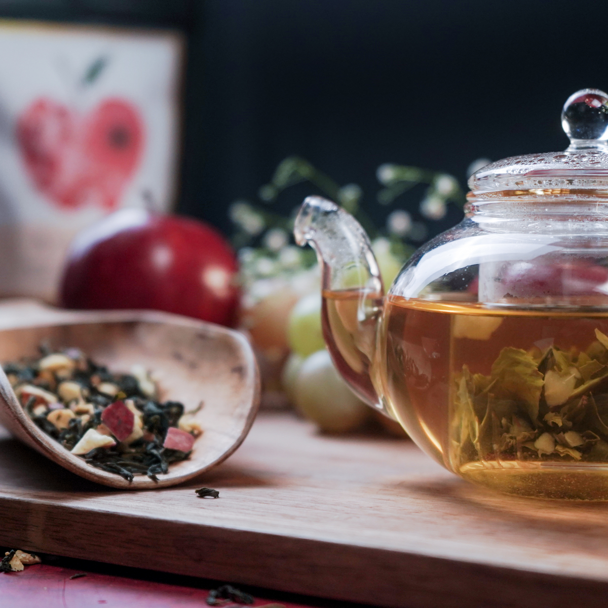 Glass teapot filled with Crisp Apple Fusion tea surrounded by fresh apples and tea leaves - ArtTeas®