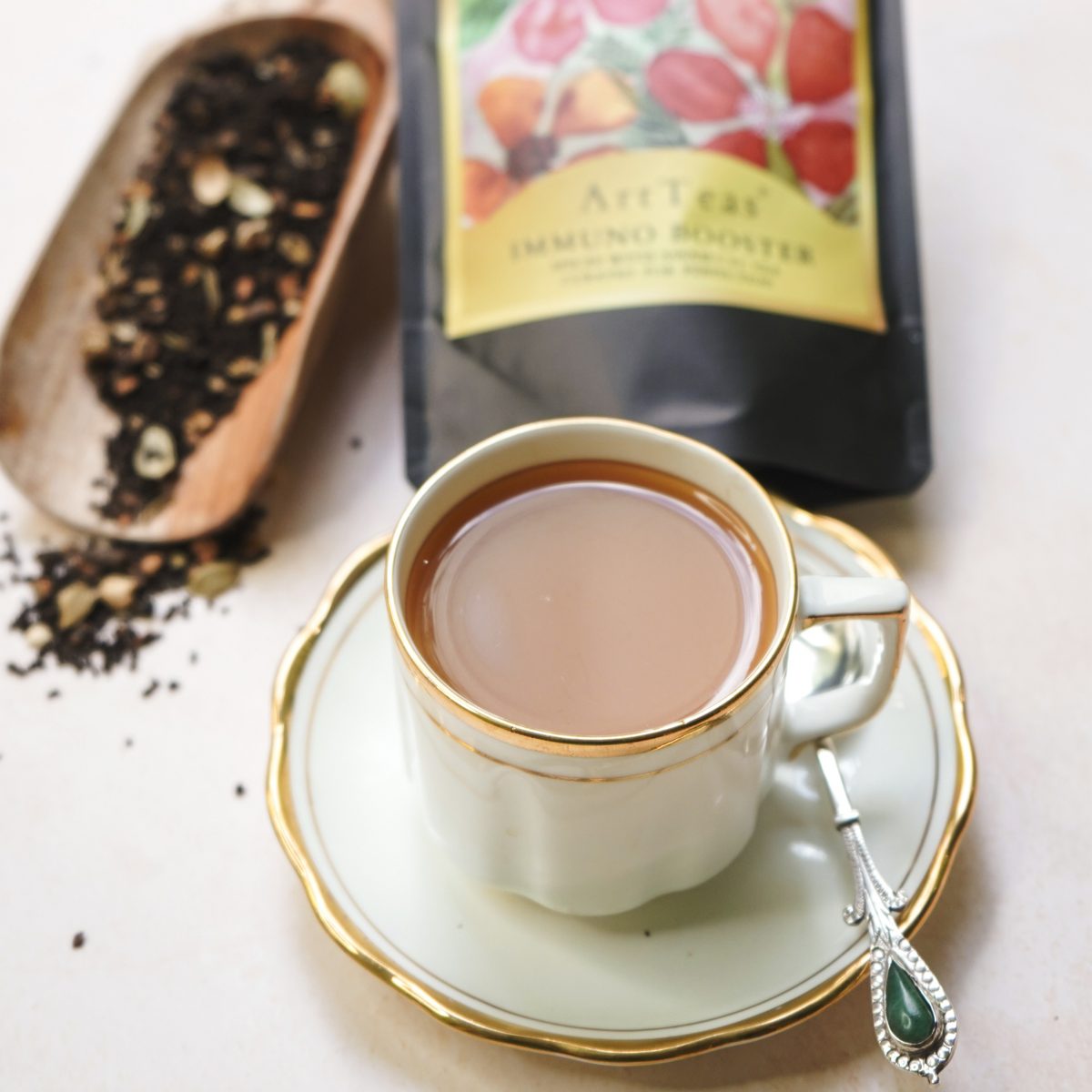 Freshly brewed Assam Masala Chai in a glass cup with loose leaf tea and ArtTeas packaging