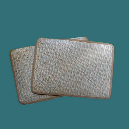 Two rectangular cane placemats with a woven pattern, displayed against a teal background.