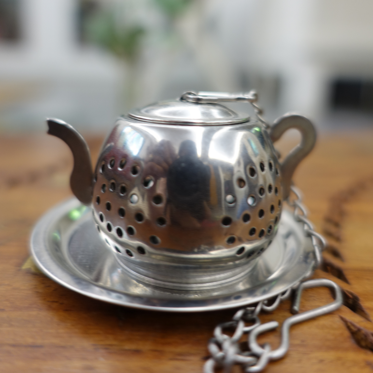Close-up view of stainless steel infuser with hanging chain for loose leaf tea - ArtTeas®