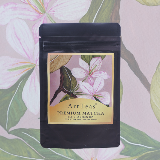 A black stand-up pouch of ArtTeas Premium Matcha tea, featuring a floral label with pink blossoms and green leaves, set against a matching floral wallpaper background.
