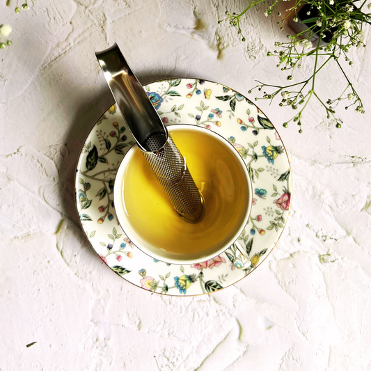 Lifestyle (infuser in cup with tea)	Stainless steel pipe infuser resting in a cup of golden loose leaf tea