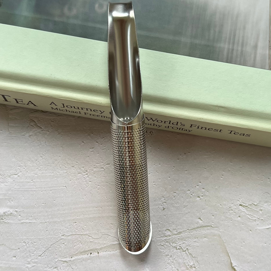 Pipe infuser for loose leaf tea shown with striped textile background